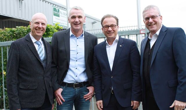 Gruppenbild von vier Männern. Alle tragen einen Anzug und schauen in die Kamera.