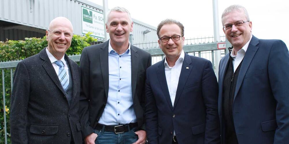 Gruppenbild von vier Männern. Alle tragen einen Anzug und schauen in die Kamera.